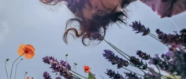 a-happy-woman-looks-into-a-flower